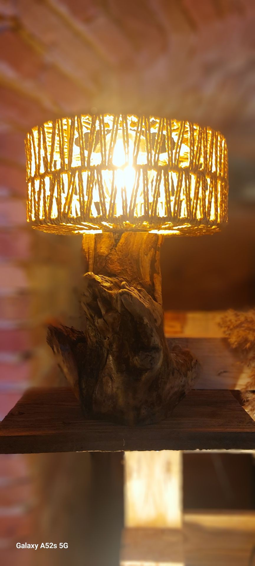 Rustic lamp with woven shade and wooden base, emitting a warm glow.