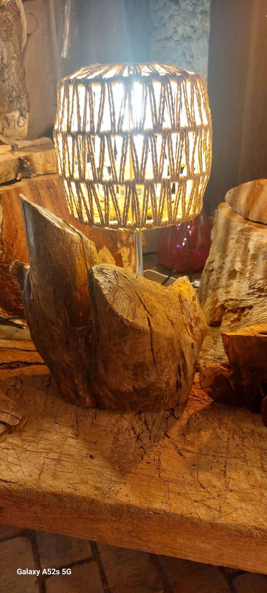 Rustic wooden lamp with woven shade on a textured wooden surface.