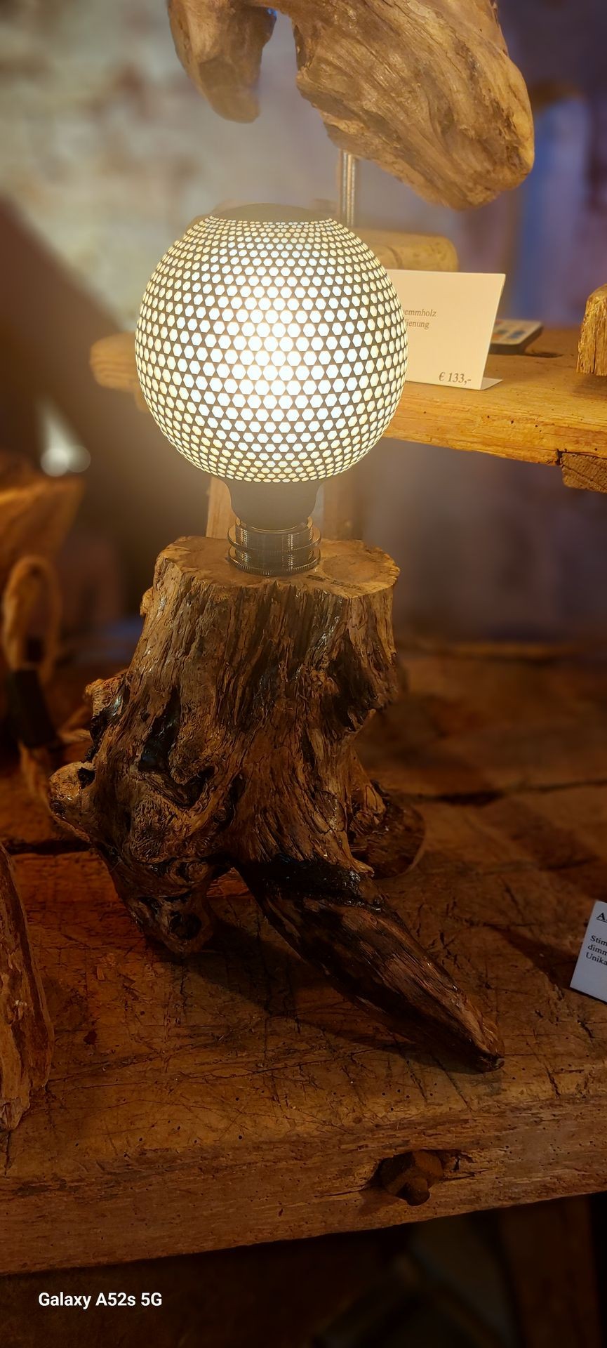 Decorative lamp with a mesh globe atop a wooden base, displayed on a wooden surface.