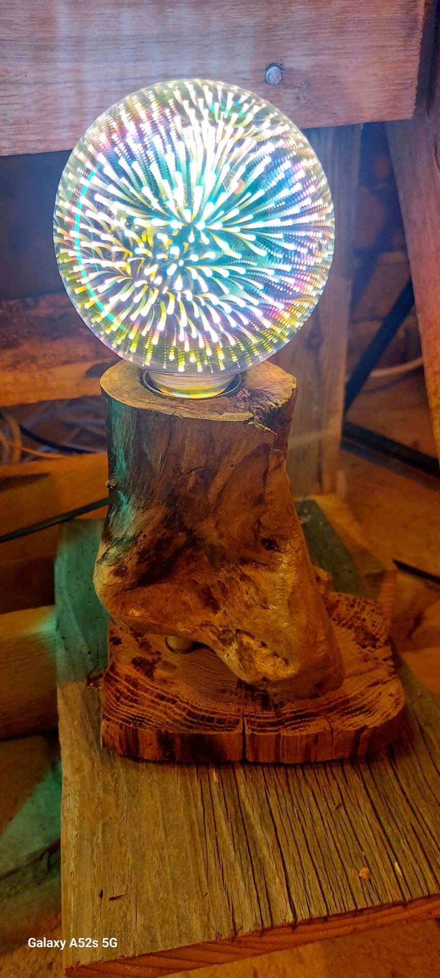 Abstract glass orb with colorful swirling patterns on wooden stand, set on rustic wooden background.