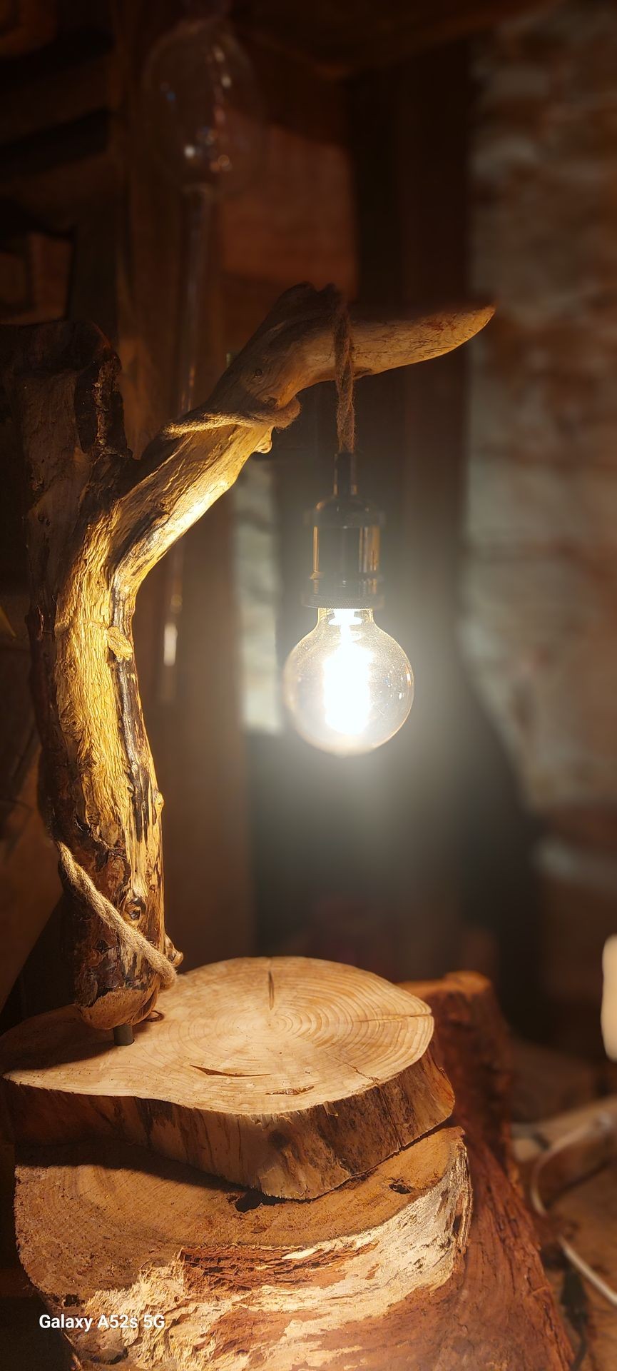 Rustic lamp with a glowing bulb attached to a wooden log base, creating a warm ambiance.